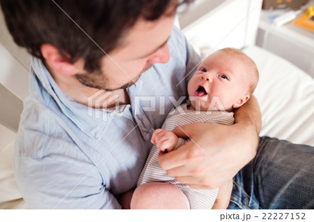 Young father holding his newborn baby son, home 22227152