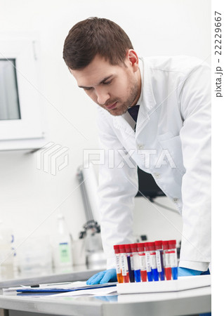 Cheerful young scientist is doing analysis in lab Cheerful young scientist is doing analysis in lab 22229667