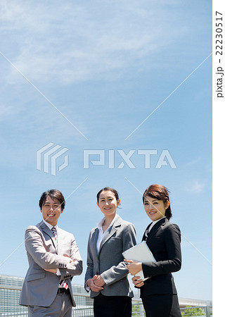 学校を背景に笑顔で並ぶ講師陣（教育・ビジネスイメージ） 22230517