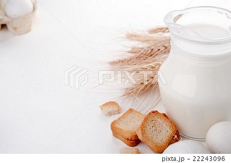Glass jug with milk, wheat seeds and two eggs  22243096