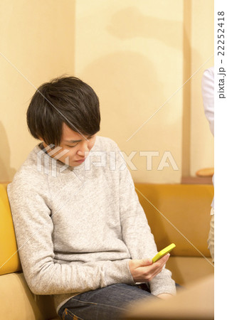 カラオケでスマホを弄る男性 22252418