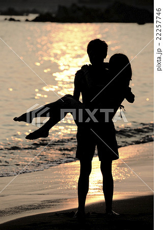 夕日の海でお姫様だっこするカップルの写真素材