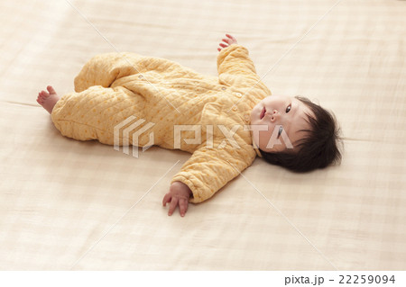 黄色い服を着て横たわる赤ちゃんの写真素材