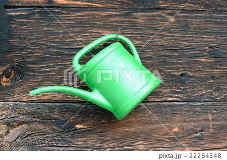 Old green plastic watering can hang on wooden wall 22264348