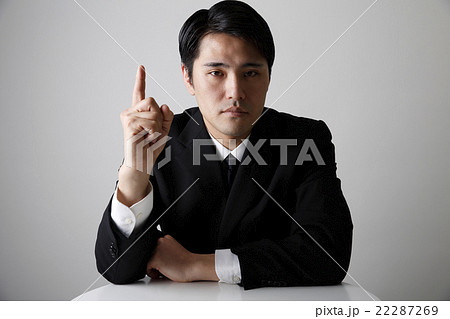 人差し指を立てるビジネススーツ姿の男性の写真素材