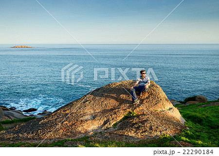 Man sitting on the edge of the rock Man sitting on the edge of the rock 22290184