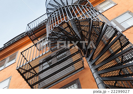 Back metal spiral ladder on the red wall Back metal spiral ladder on the red wall 22299027