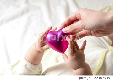 ハートを持つ赤ちゃんとお母さんの手の写真素材