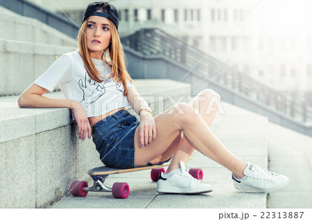 Beautiful young girl in skirt sits with longboard Beautiful young girl in skirt sits with longboard 22313887