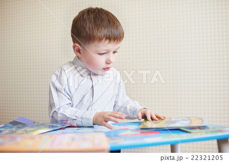 Little boy is sitting at the desk and read book Little boy is sitting at the desk and read book 22321205
