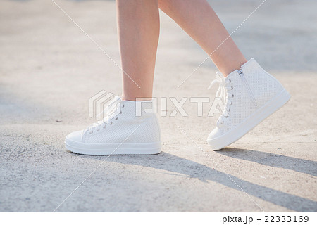 Woman In White Sneakers Walking Under Sunlightの写真素材