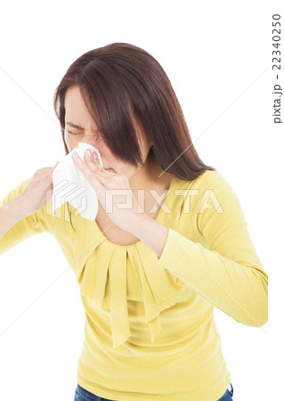 young woman using a tissue and blowing nose 22340250