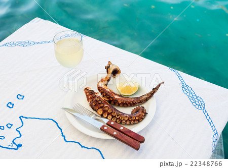 Grilled octopus and white wine glass on a table at 22348766