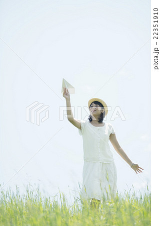 草原で紙飛行機を飛ばす女性 22351910