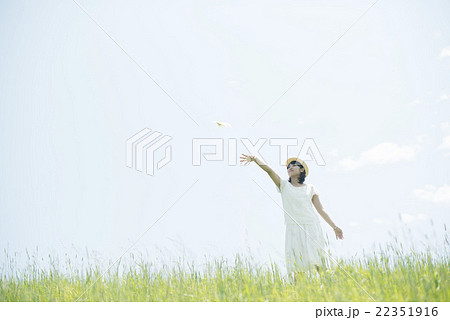 草原で紙飛行機を飛ばす女性 22351916