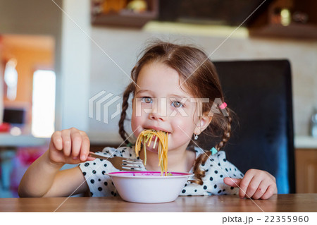 Little girl in the kitchen smiling, eating 22355960