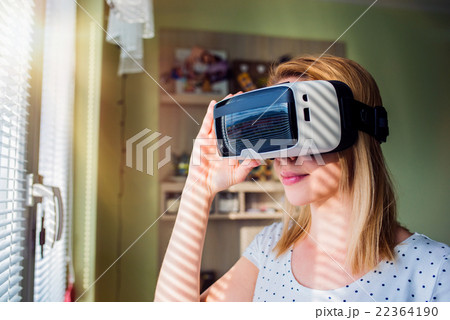 Woman wearing virtual reality goggles standing in 22364190