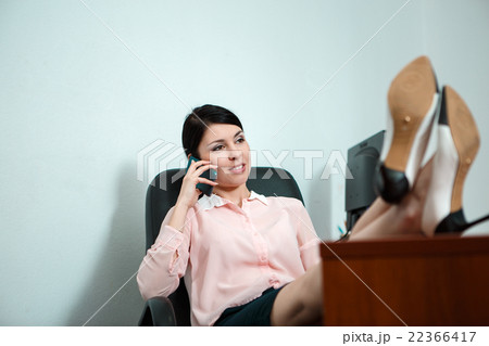 Relaxed business woman sitting in a chair with 22366417