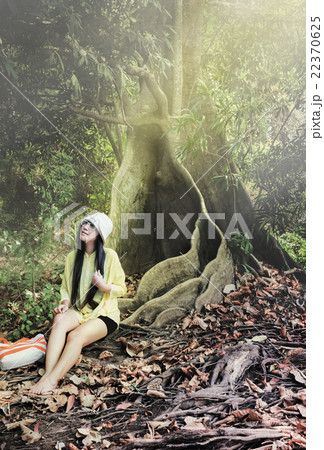 Smiling Asian women in relax summer dress sitting under big tree 22370625