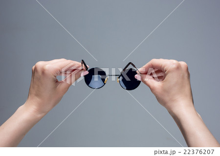The female hands holding sunglasses on gray 22376207