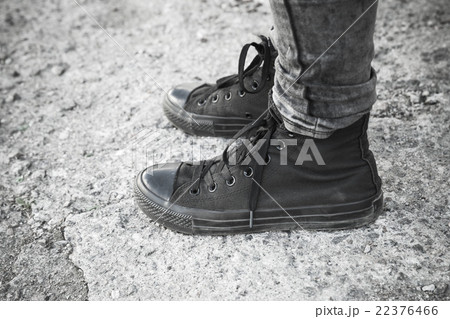 Teenager feet in black gumshoes and jeans Teenager feet in black gumshoes and jeans 22376466