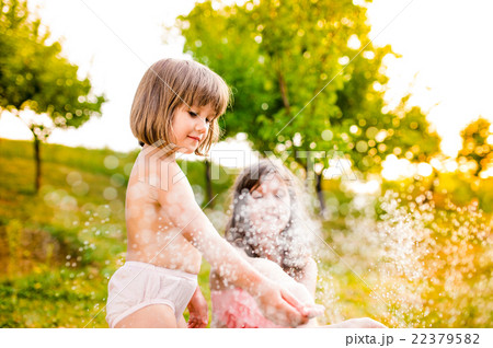 Two girls at the sprinkler, sunny summer in the 22379582