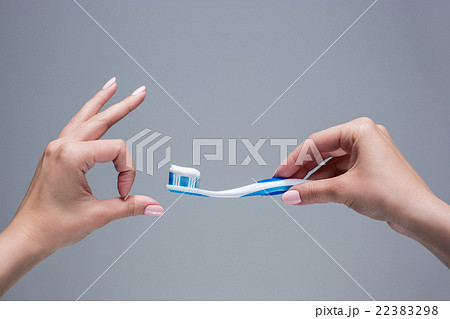 Toothbrush in woman's hands on gray 22383298