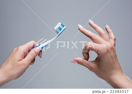 Toothbrush in woman's hands on gray 22383317