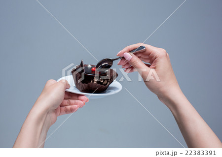 Female hands keeping cake with spoon on gray Female hands keeping cake with spoon on gray 22383391
