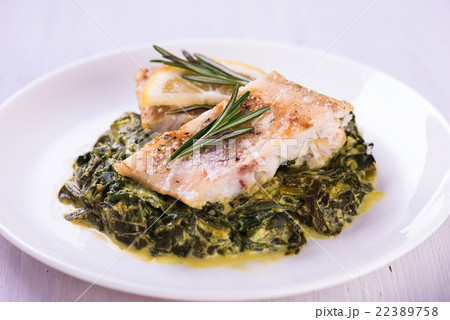 white fish fillet with herbs on fried spinach white fish fillet with herbs on fried spinach 22389758