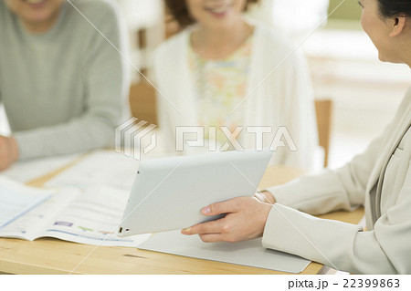 シニア夫婦にタブレットPCで説明をするビジネスウーマン 22399863