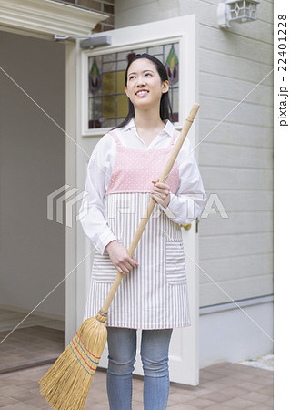 玄関前でほうきを持つ日本人女性の写真素材