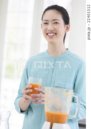 ジュースの入ったコップを持つ女性の写真素材