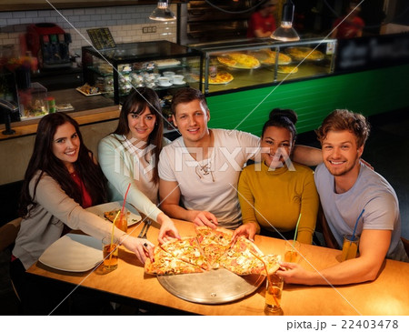 Multiracial friends eating pizza in pizzeria. 22403478