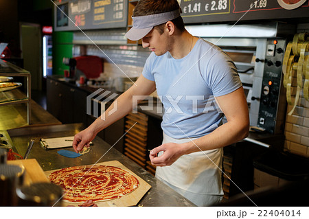 Handsome pizzaiolo making pizza at kitchen in pizzeria. Handsome pizzaiolo making pizza at kitchen in pizzeria. 22404014