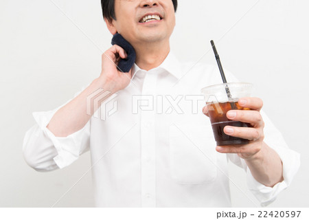 汗を拭きながらアイスコーヒーを飲むビジネスマン 22420597