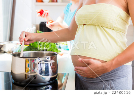 Pregnant woman cooking with best friend Pregnant woman cooking with best friend 22430516
