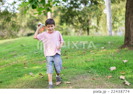 Little sibling boy playing plane paper in the park 22438774