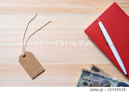 ヒノキのテーブルに置かれたタグと手帳とお金 ラベル 値札 背景素材 の写真素材