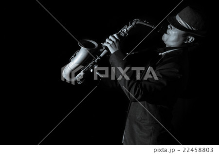 A saxophone player in a dark background, black and white tone 22458803