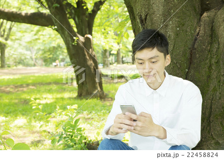 スマホ　男性　カジュアル　考える　見つめる　ポートレート　外　公園　緑 22458824