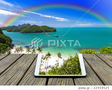 Conceptual image of a teblet on the wooden table on Top view of Ang Thong National Marine Park with rainbow, Thailand 22459525