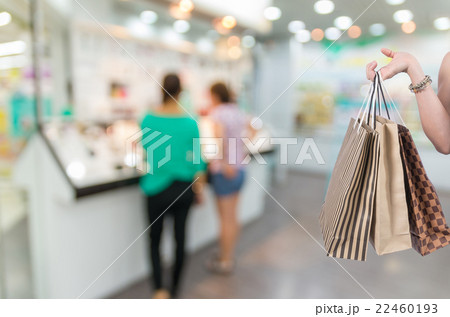 Holding shopping bags by hand on Supermarket with Abstract blurred photo of cosmatic store in department store bokeh background Holding shopping bags by hand on Supermarket with Abstract blurred photo of cosmatic store in department store bokeh background 22460193