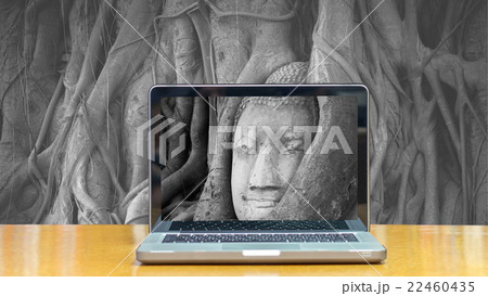 Conceptual image of a computer laptop on Head of sand stone buddha in a tree at Wat Mahathat, Ayutthaya, Thailand, public temple 22460435