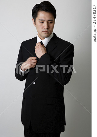 ネクタイを締めるビジネススーツ姿の男性の写真素材