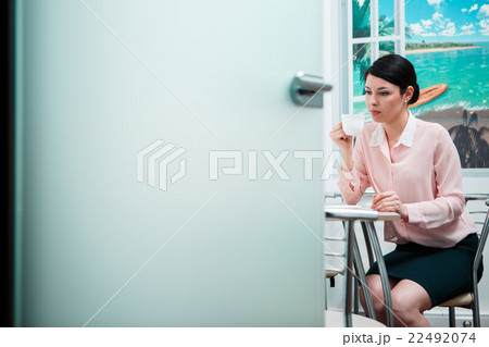 Woman drinking coffee in office kitchen 22492074