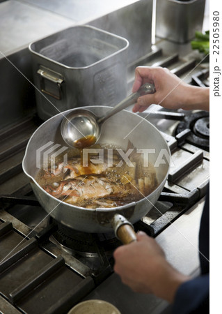 煮汁をかけながら魚を煮る調理師 22505980