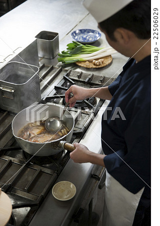 煮汁をかけながら魚を煮る調理師 煮汁をかけながら魚を煮る調理師 22506029