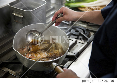 煮汁をかけながら魚を煮る調理師 煮汁をかけながら魚を煮る調理師 22506136