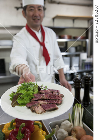 ステーキの皿を差し出す調理師の写真素材
